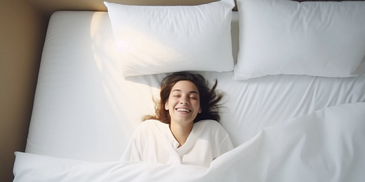 Donna sorridente nel letto avvolta da piumino estivo in piuma d'oca