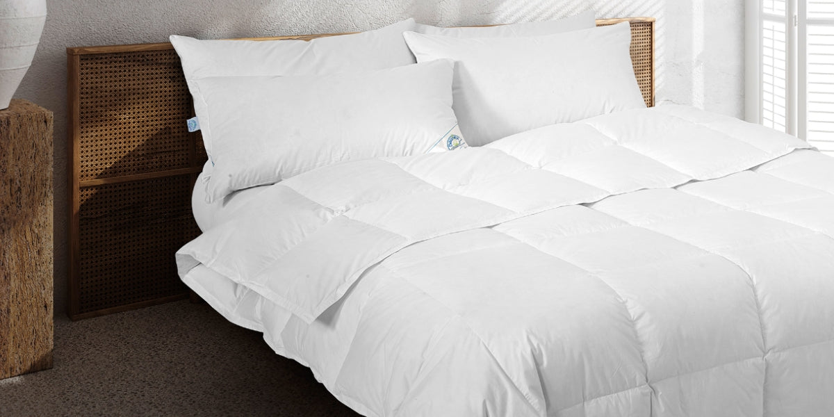 Piumino matrimoniale in piuma d'oca bianco su letto in legno