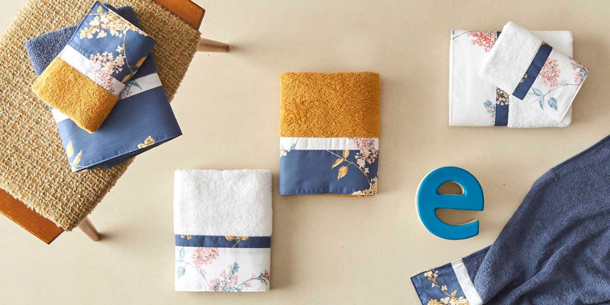 Asciugamani in spugna colorati con balza in percalle sul pavimento e sopra un tavolino